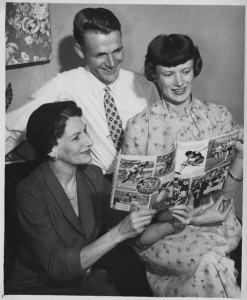 Man with two women looking at a track and field magazine together.