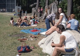 People gathered at a park sitting along the sidelines to watch a softball game.