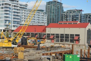 Cityscape with construction site and crane in foreground and The Shipyards buildings in background.