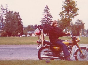 Man sitting on a motorcycle with trees in the background.