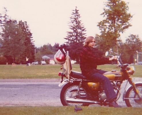 Man sitting on a motorcycle with trees in the background.