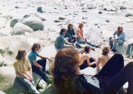 Several men sitting on rocks next to a stream.