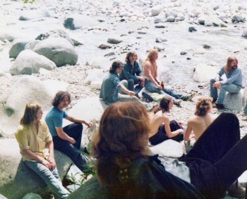Several men sitting on rocks next to a stream.