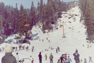 Landscape shot showing ski hill, chair lift, skiers and spectators.