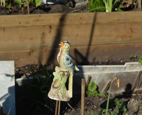 Vintage ceramic bird ornament in a garden.
