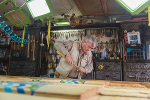 Indigenous carver in workshop carving large wood piece for entrance to MONOVA museum.