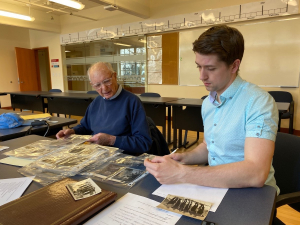 Archives and Community Engagement Intern Alec Postlethwaite reviews historical photos with Harold Enqvist Jr. following an oral history interview. Photo: Jessica Bushey