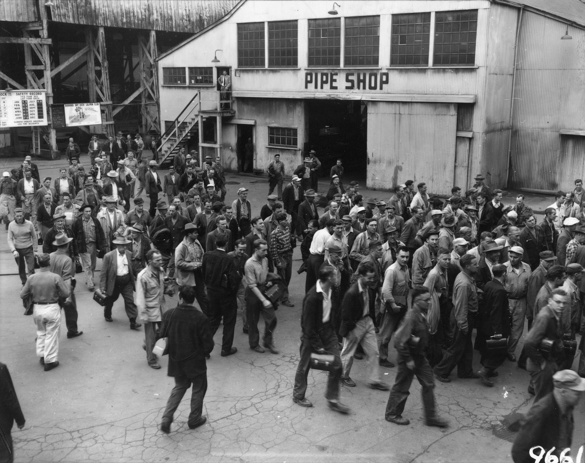 Employees walking past the end of the Pipe Shop, Burrard Dry Dock. Pipe Shop sign is clearly visible, 14 August 1957. Photo: Jack Cash, NVMA 10431