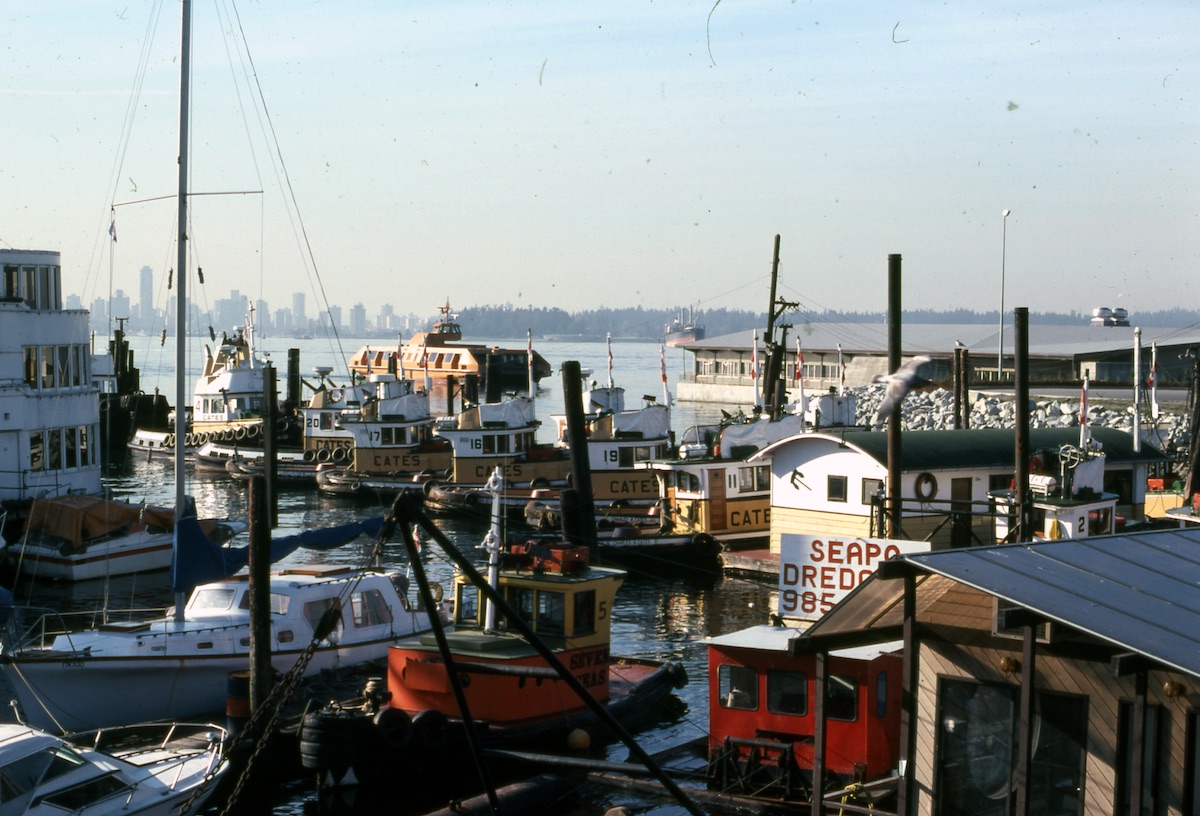 A view of a dock at the foot of Lonsdale Avenue, with leisure boats and Cates tugs docked in the foreground, and a SeaBus arriving at the terminal in the background, November 1978. Photo: Bruce Flanagan, NVMA 160-168